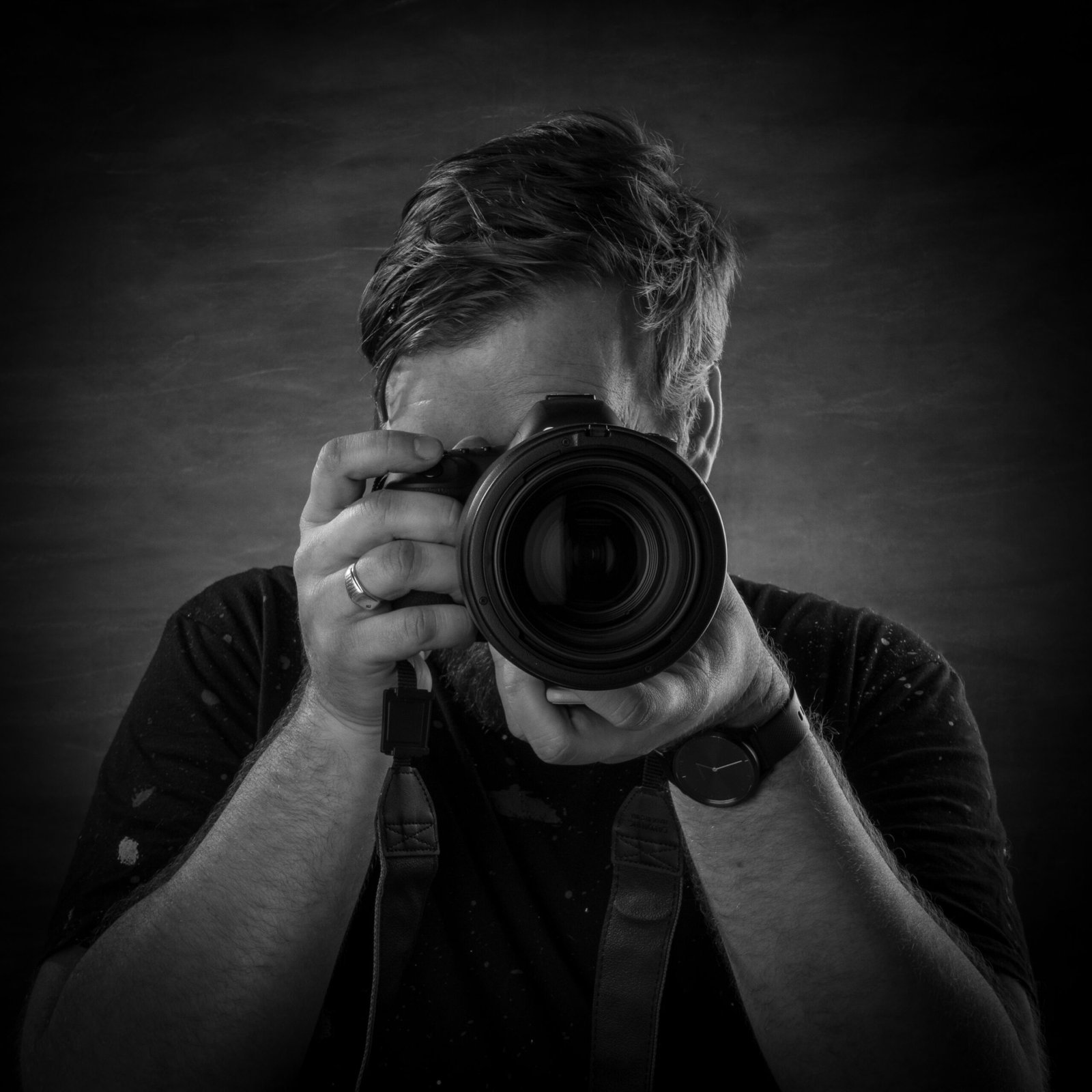 A Black and White Portrait of Tristan McCool holding a camera up to his face